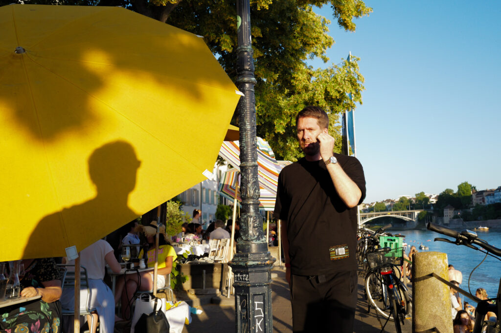 Shadow of a man cast on a yellow umbrella by the Rhine in Basel